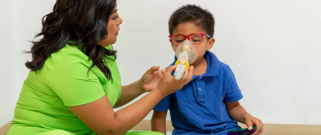 respiratory therapist assisting child using nebulizer for breathing treatment